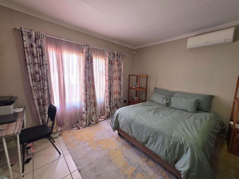 A functional bedroom featuring tiled flooring and a wall-mounted split-system air conditioner, providing a comfortable and climate-controlled living space.