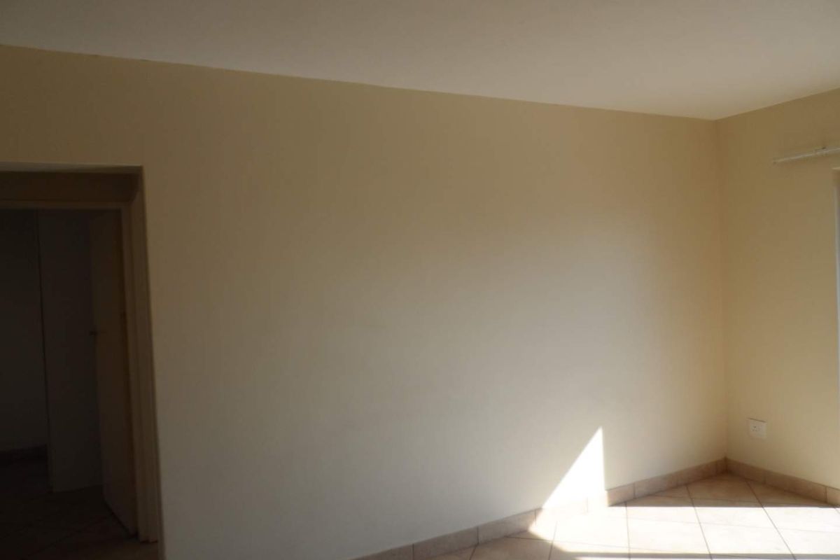 A bright, empty living area featuring neutral wall tones and tiled flooring, providing a clean canvas for interior design.
