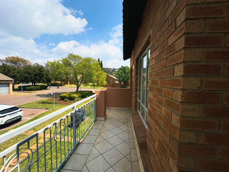 A clean, tiled balcony featuring a metal balustrade and face brick exterior wall, overlooking the complex grounds.