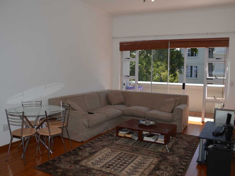 A living room featuring laminate flooring and a large sliding glass door that provides access to an outdoor balcony area.