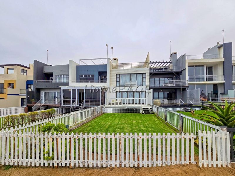 Rear view of a multi-level residential property featuring private balconies, wooden decking, and a fenced garden area.