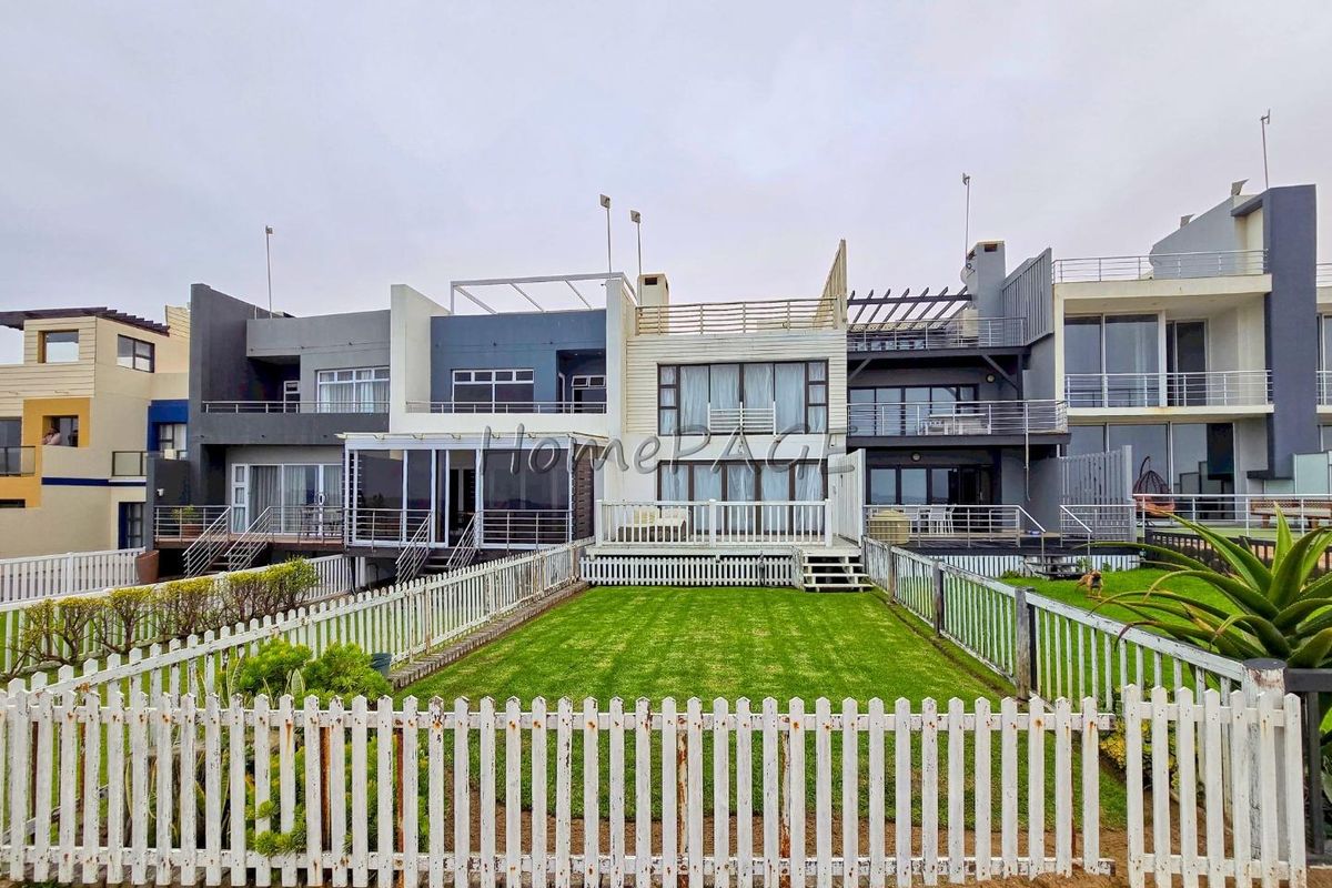 Rear view of a multi-level residential property featuring private balconies, wooden decking, and a fenced garden area.