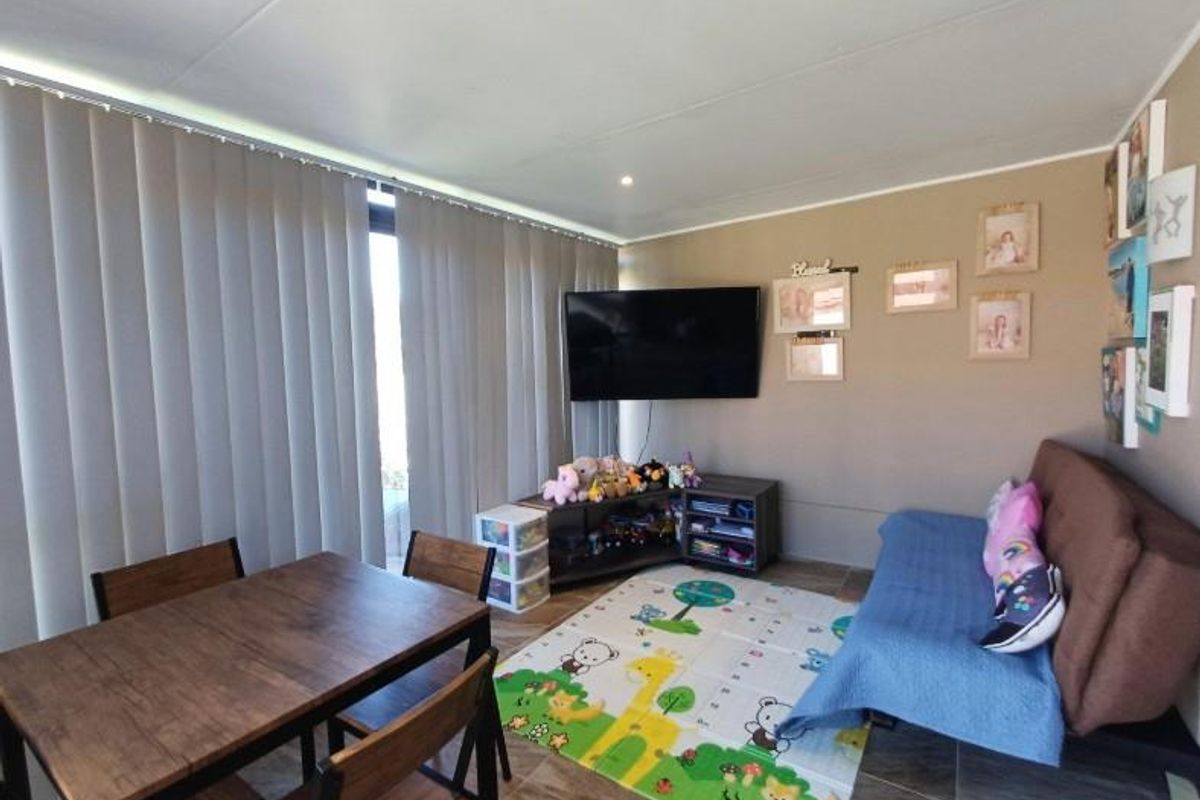 A functional living area featuring tiled flooring, vertical blinds, and recessed ceiling lighting, providing a versatile space for relaxation and dining.