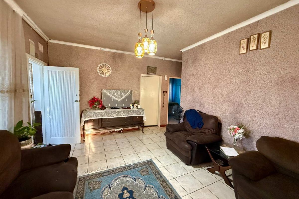 A living room featuring tiled flooring and textured wall finishes, providing a functional space with potential for modernization.