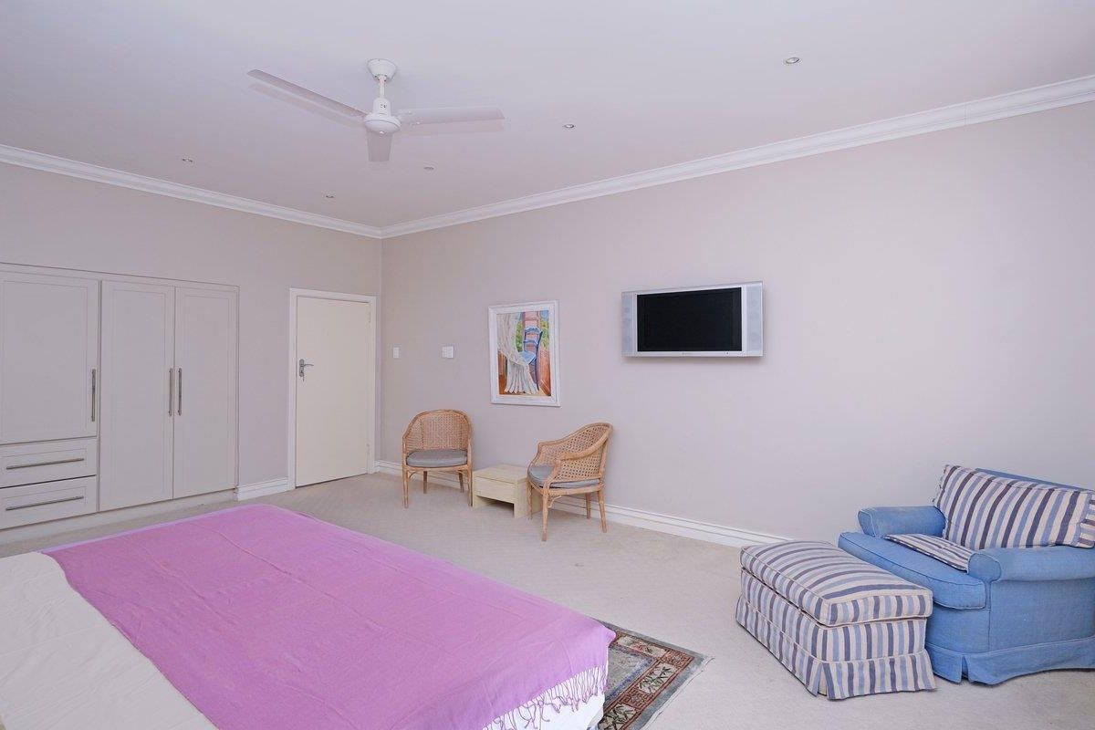 Spacious bedroom featuring built-in cupboards, neutral carpeting, crown molding, and a ceiling fan, offering a comfortable and well-maintained living space.
