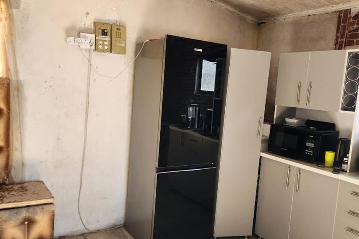 A dated kitchen area featuring tiled floors, built-in cabinetry, and a timber panelled ceiling, currently showing signs of wear and requiring cosmetic updates.