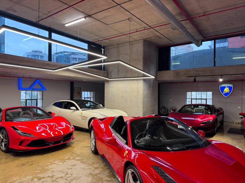 Modern industrial-style garage space featuring exposed concrete ceilings, polished concrete floors, and contemporary linear lighting fixtures.