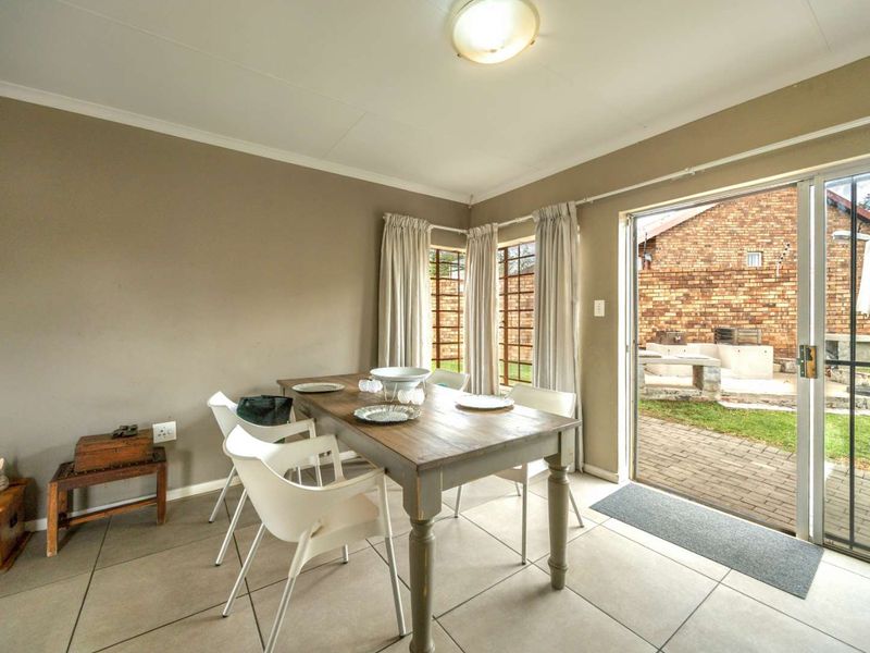 Dining area featuring neutral wall tones, tiled flooring, and a sliding glass door providing direct access to the rear patio and garden.