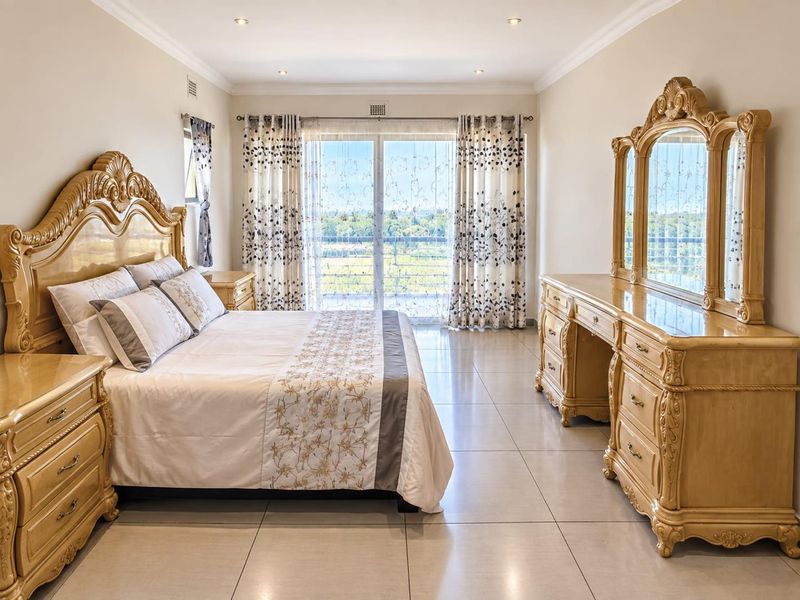 Spacious bedroom featuring large format floor tiles, recessed lighting, and sliding glass doors providing access to a balcony with scenic views.