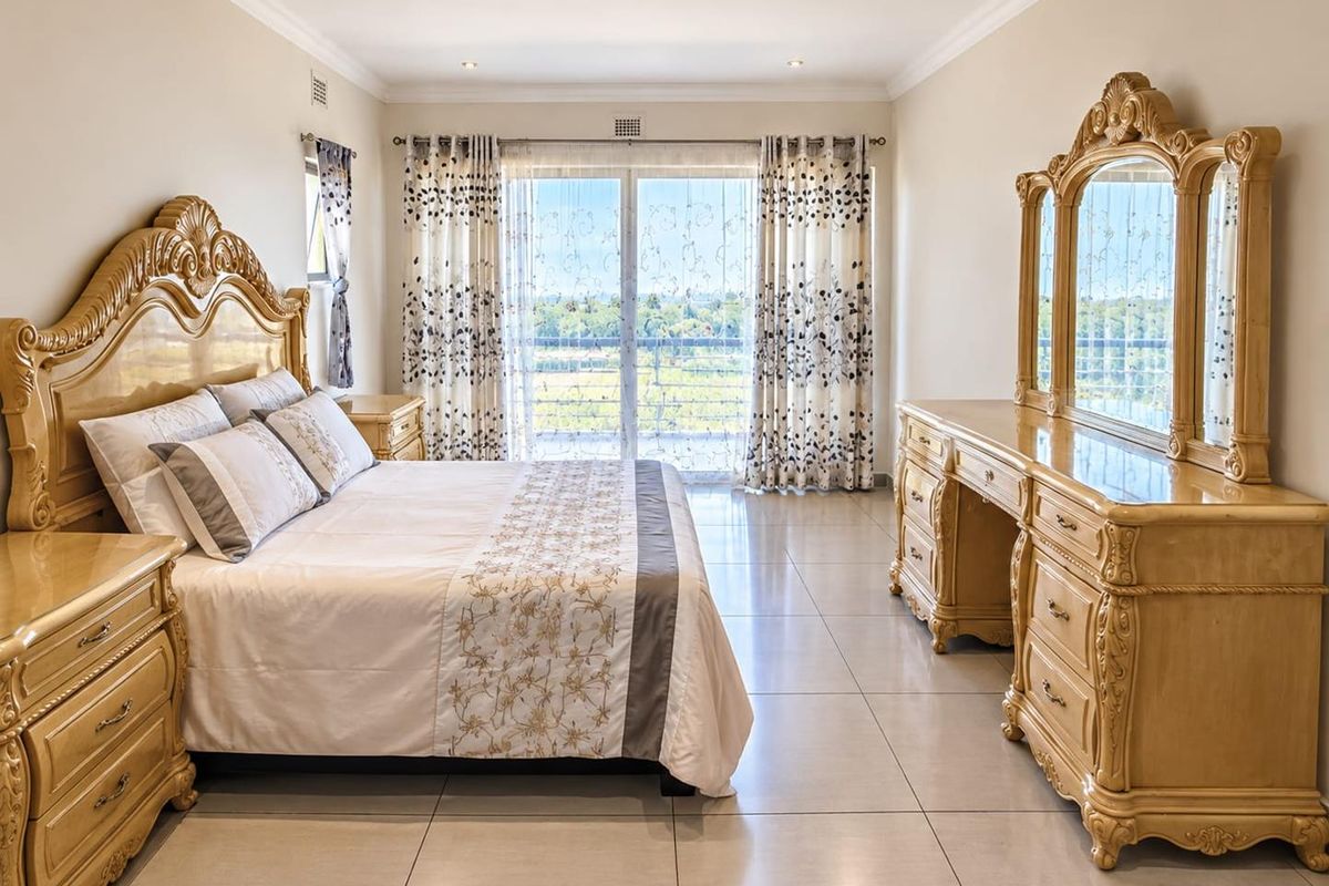 Spacious bedroom featuring large format floor tiles, recessed lighting, and sliding glass doors providing access to a balcony with scenic views.