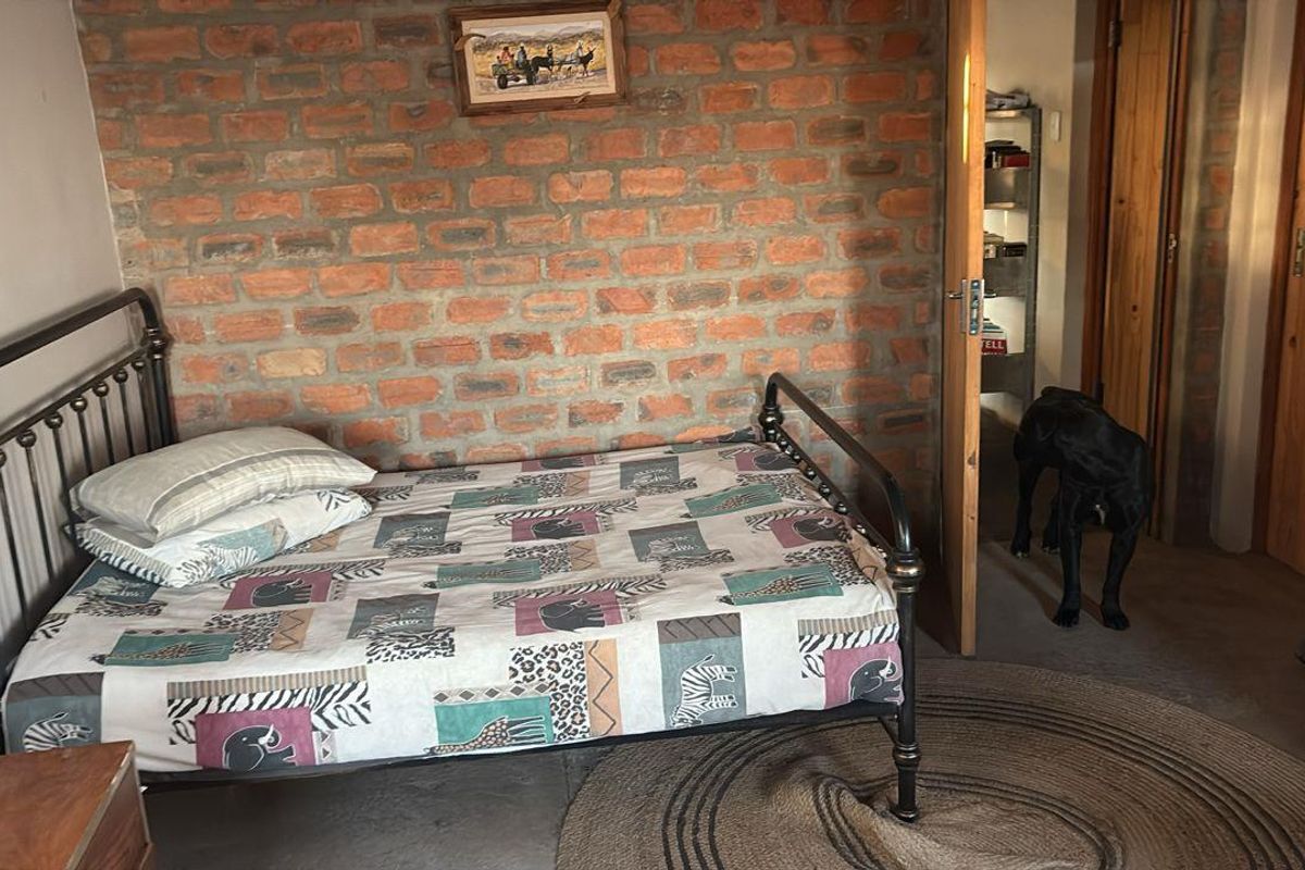 A rustic bedroom featuring an exposed brick feature wall and wooden door frame, providing a warm, traditional farm-style aesthetic.