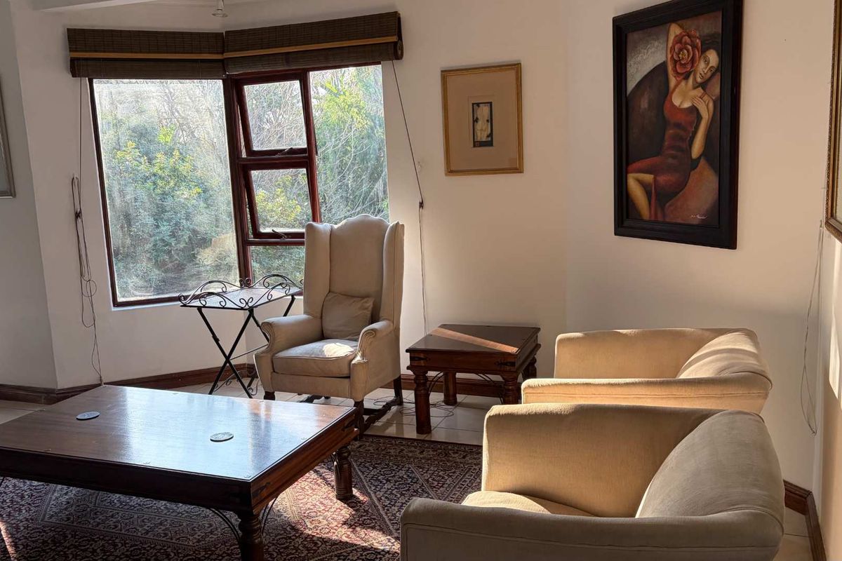 A bright living room featuring a large bay window with natural light, tiled flooring, and neutral wall finishes.