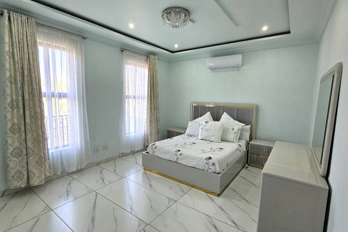 Spacious bedroom featuring modern marble-look floor tiles, recessed ceiling lighting, and a wall-mounted air conditioning unit.