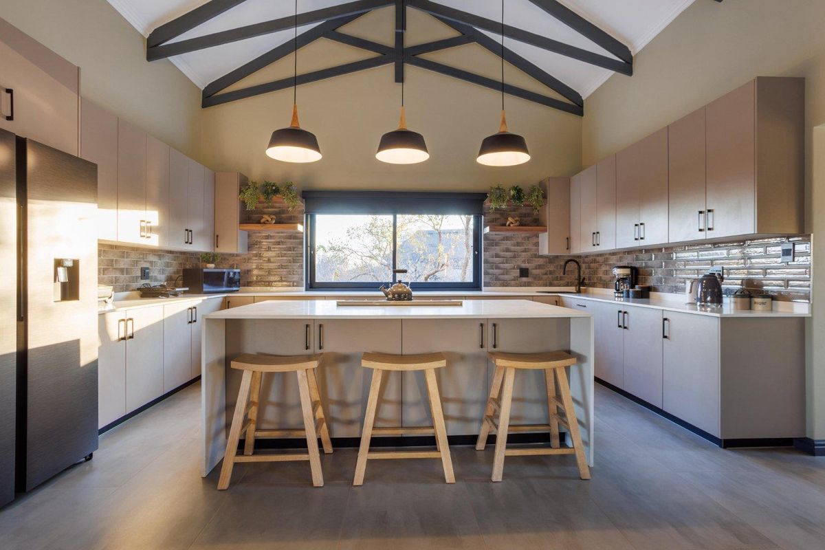 Modern kitchen featuring a central island, sleek cabinetry, subway tile backsplash, and striking exposed ceiling trusses with pendant lighting.