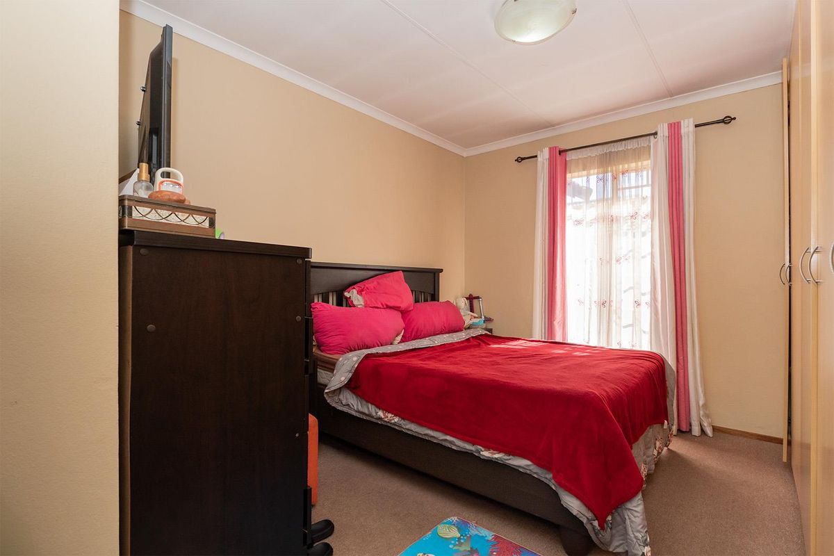 A standard bedroom featuring built-in cupboards and carpeted flooring, providing a functional living space.