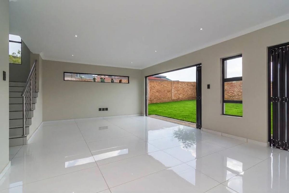 Spacious, modern open-plan living area featuring polished tile floors, recessed lighting, and large stacking doors opening onto a private rear garden.