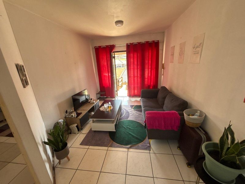A compact living room featuring tiled flooring and a sliding glass door providing access to an outdoor area.