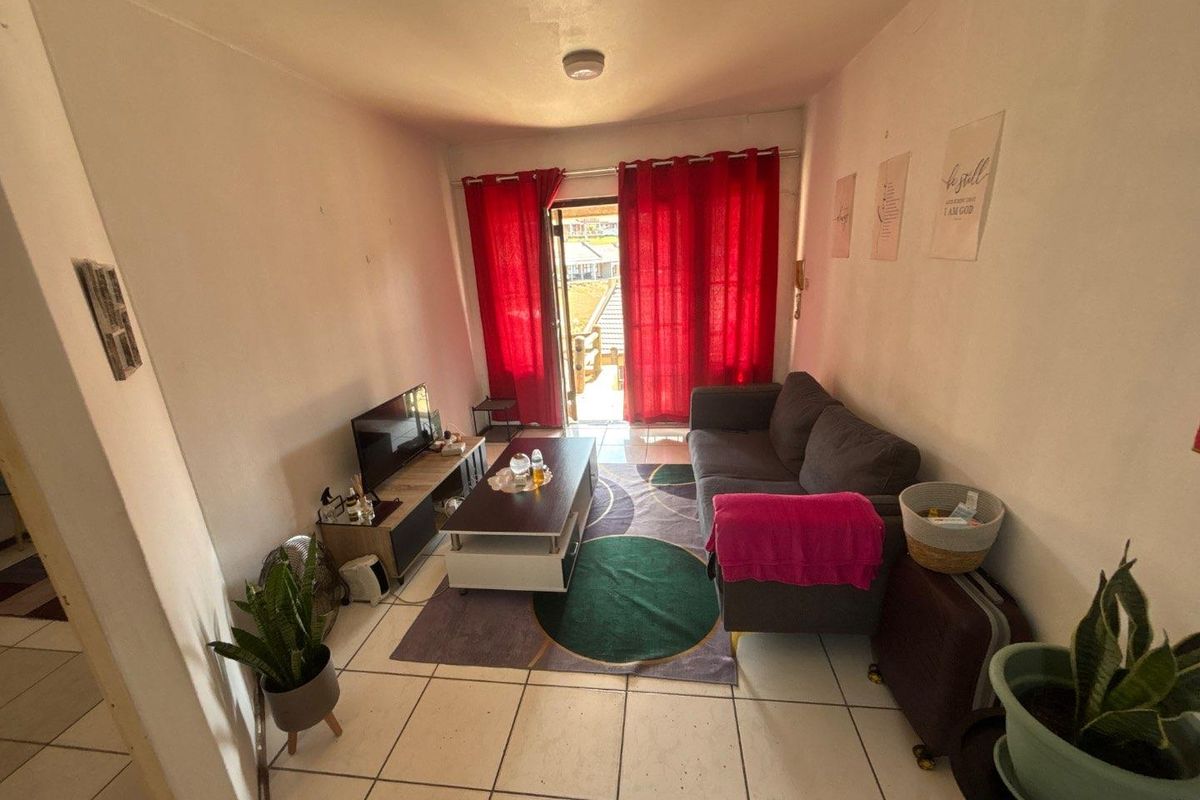 A compact living room featuring tiled flooring and a sliding glass door providing access to an outdoor area.