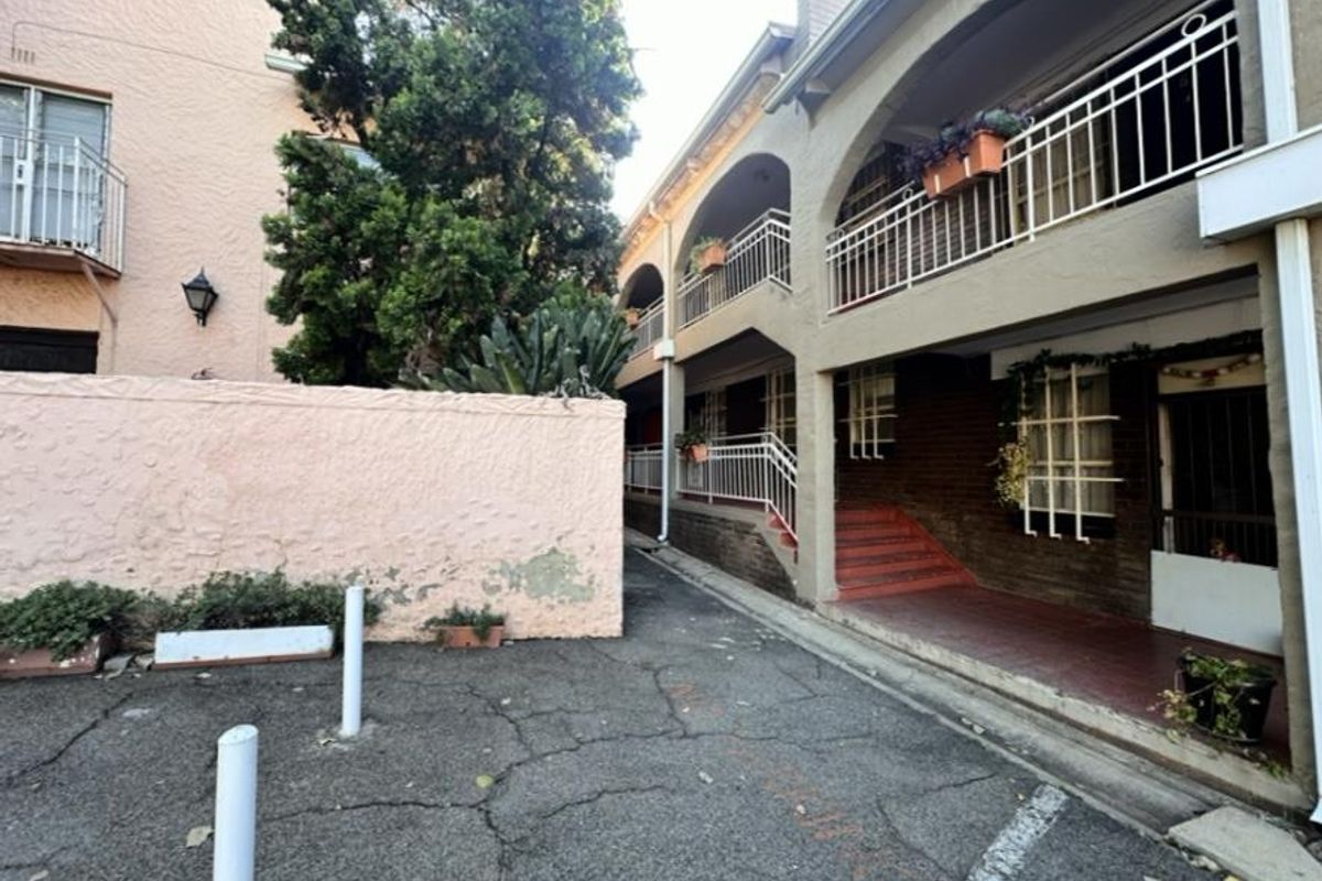 Exterior view of an apartment complex featuring a paved driveway, brick facade, and multi-level balconies with metal railings.