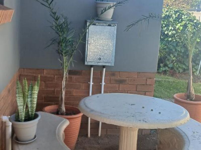 A small outdoor patio area featuring a brick base wall, tiled roof overhang, and an exterior electrical distribution box.