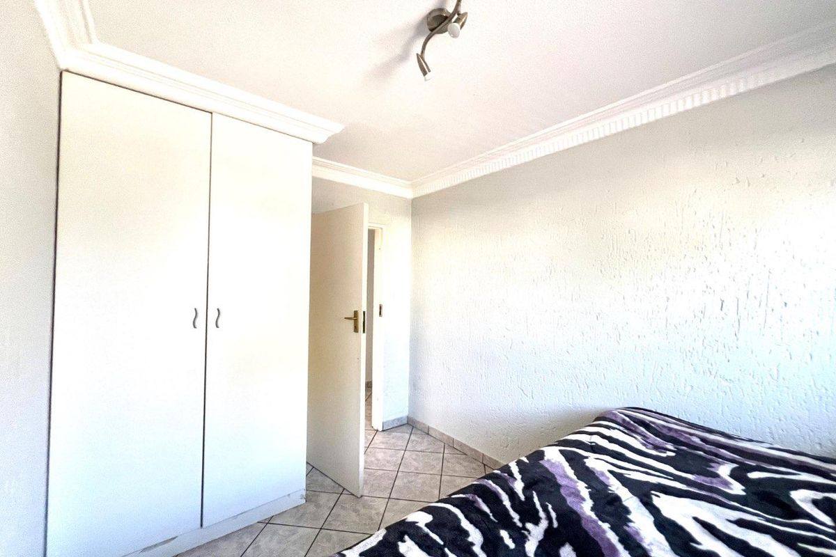 A bedroom featuring built-in cupboards, tiled flooring, and decorative ceiling cornicing.