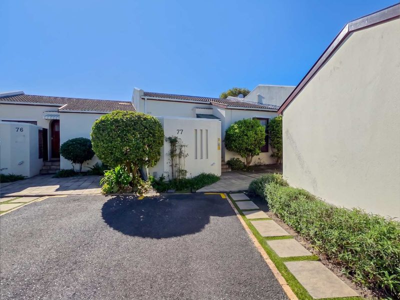 Front exterior view of the property featuring a paved driveway, tiled roof, and well-maintained garden entrance.