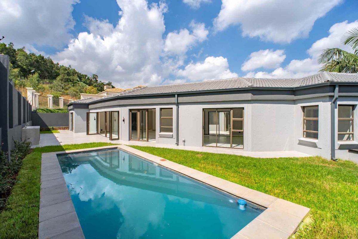 Rear view of the property featuring a swimming pool, manicured lawn, paved patio area, and large sliding glass doors providing seamless indoor-outdoor flow.