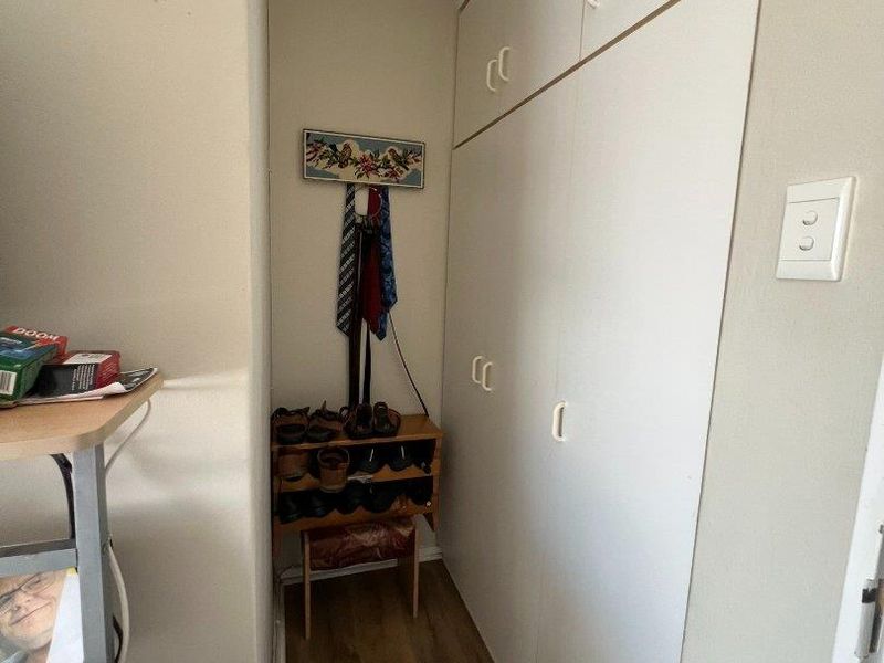 A narrow hallway featuring floor-to-ceiling built-in cupboards and durable laminate flooring, providing practical storage space within the home.