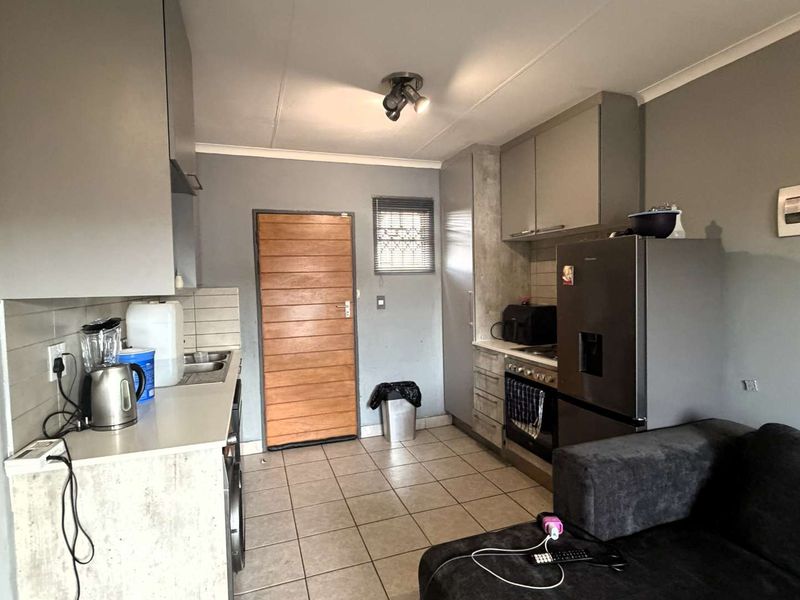 Open-plan kitchen and living area featuring tiled flooring, built-in cabinetry, and integrated cooking appliances, providing a functional and compact living space.