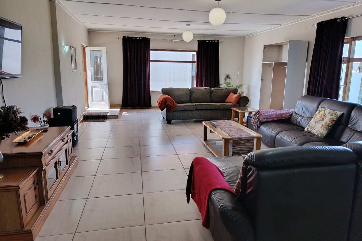 Spacious living room featuring large windows, tiled flooring, and a neutral color palette, providing a comfortable and functional family living space.