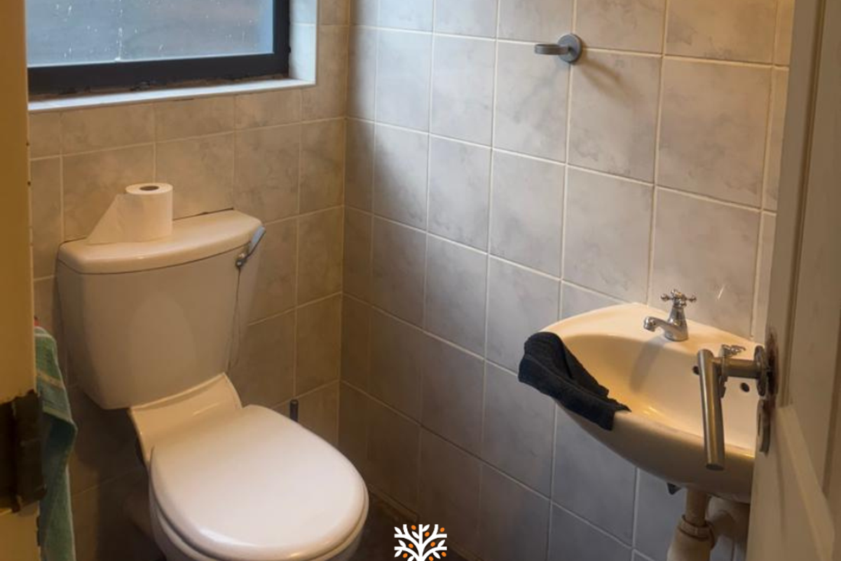 A compact guest bathroom featuring a standard toilet and a wall-mounted basin with tiled walls.
