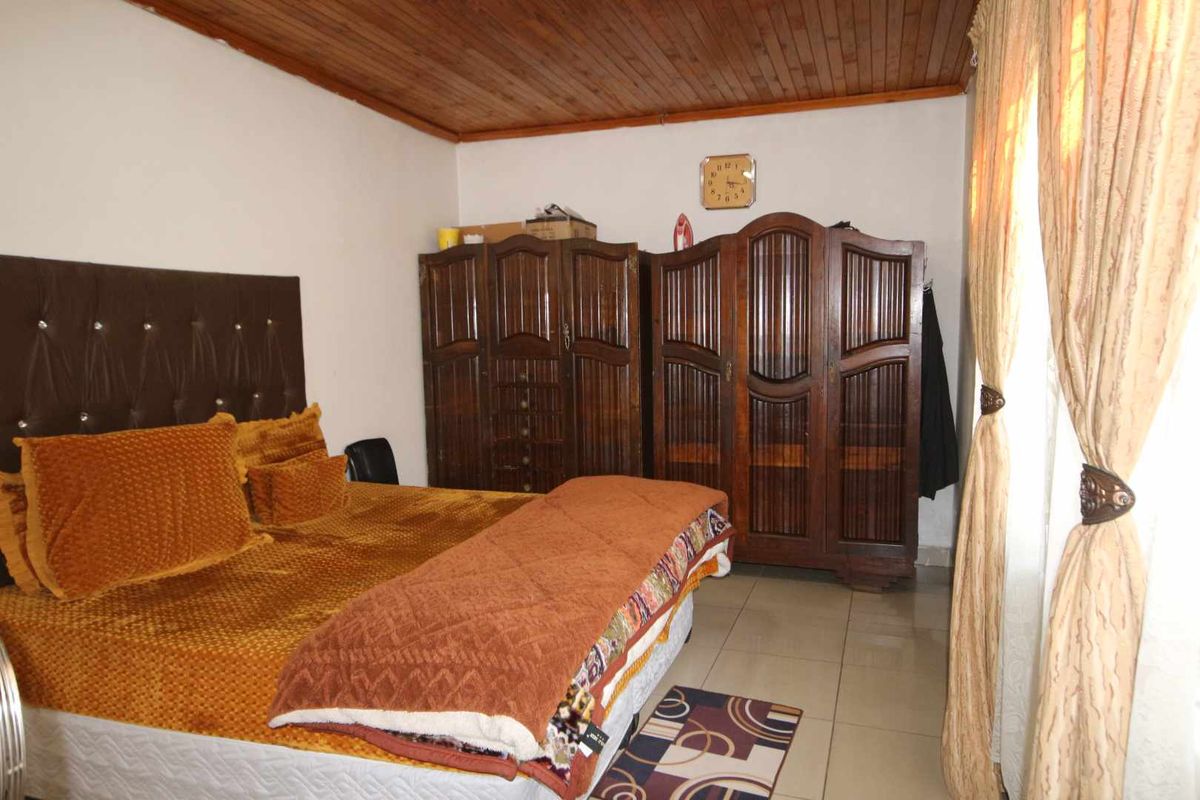 A bedroom featuring a timber-clad ceiling and tiled flooring, providing a functional space with traditional finishes.