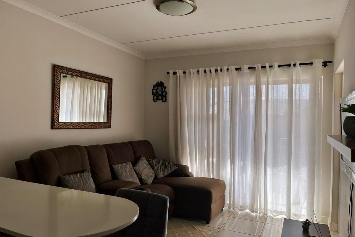 A comfortable living area featuring tiled flooring, a ceiling-mounted light fixture, and large sliding glass doors that provide access to the exterior.