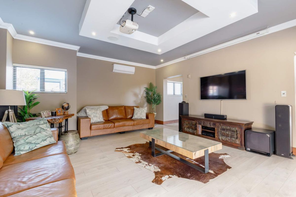 Spacious living room featuring a recessed tray ceiling with integrated projector, split system air conditioning, and modern laminate flooring.