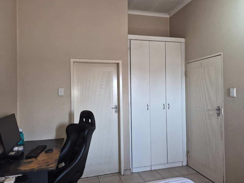 A bedroom featuring tiled flooring and a built-in wardrobe, providing functional storage space within the apartment.