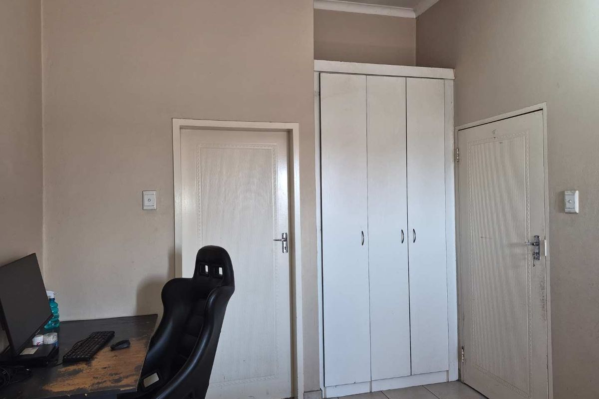 A bedroom featuring tiled flooring and a built-in wardrobe, providing functional storage space within the apartment.
