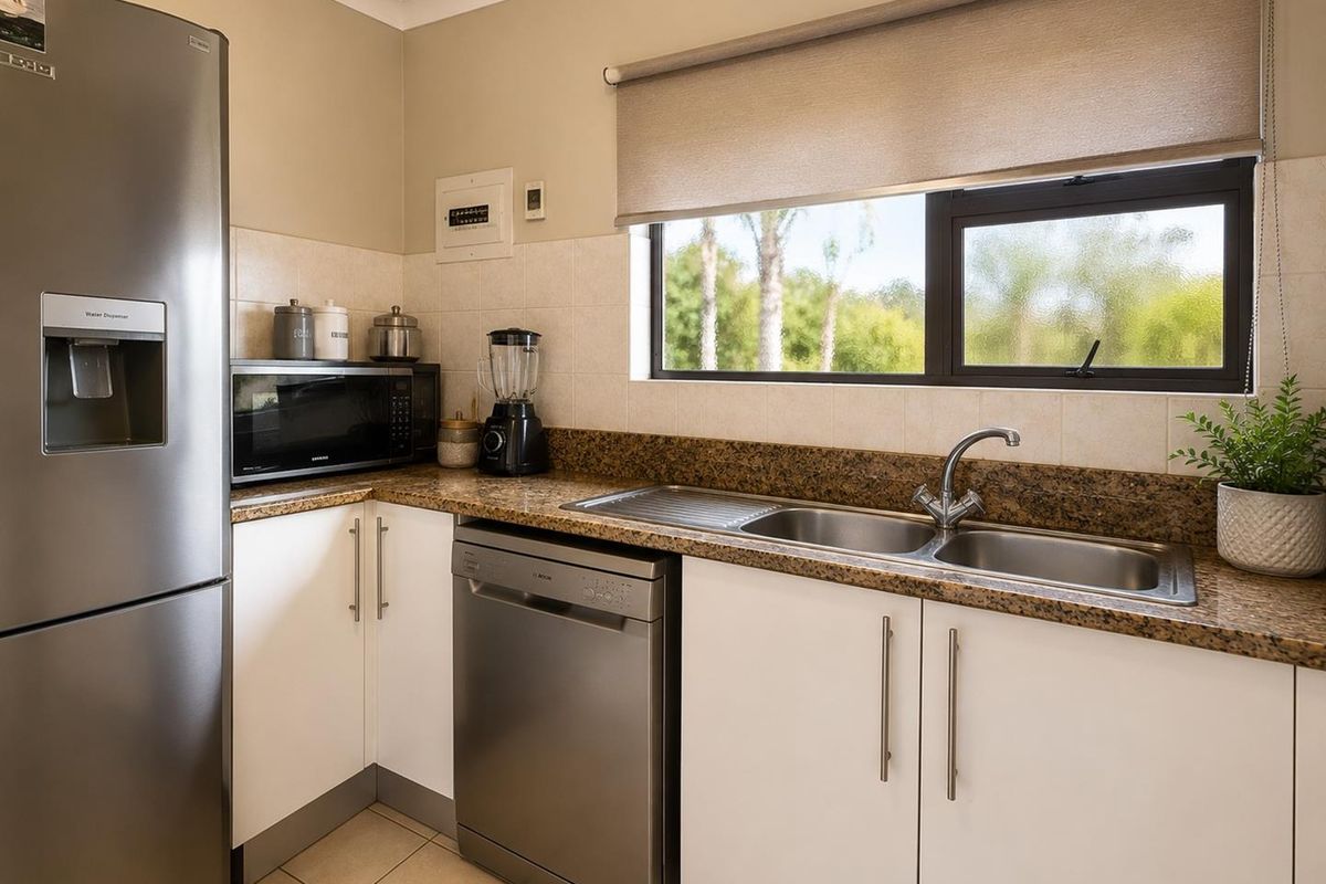 A functional kitchen featuring granite countertops, a stainless steel double sink, and white cabinetry with a tiled backsplash and window view.
