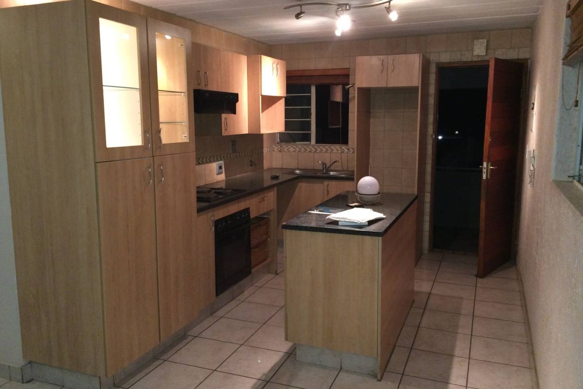 A functional kitchen featuring light wood cabinetry, granite countertops, a central island, built-in oven, and tiled flooring.