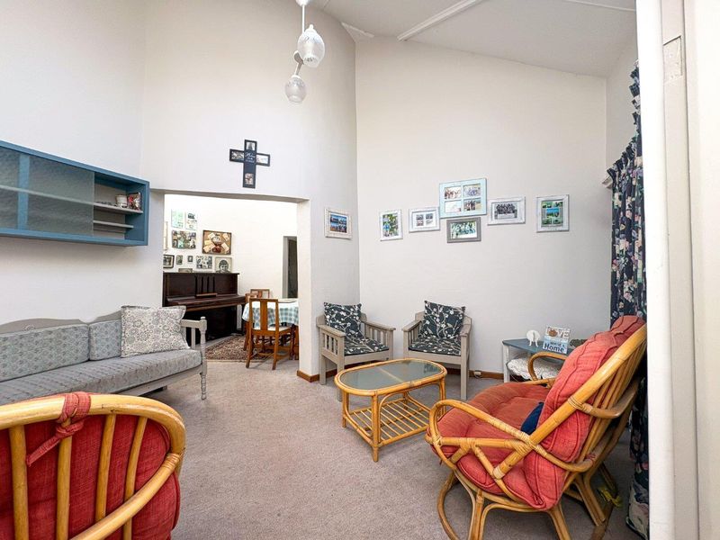 A spacious living room featuring a high vaulted ceiling and built-in wall shelving, offering a bright and open atmosphere.