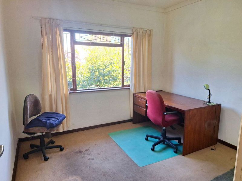 A functional home office space featuring a window with security bars and carpeted flooring, offering a quiet area for work or study.