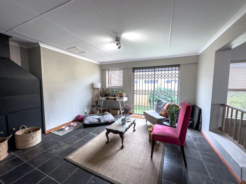 A living room featuring slate tile flooring, a built-in fireplace, and a sliding glass door with a security gate leading to the exterior.
