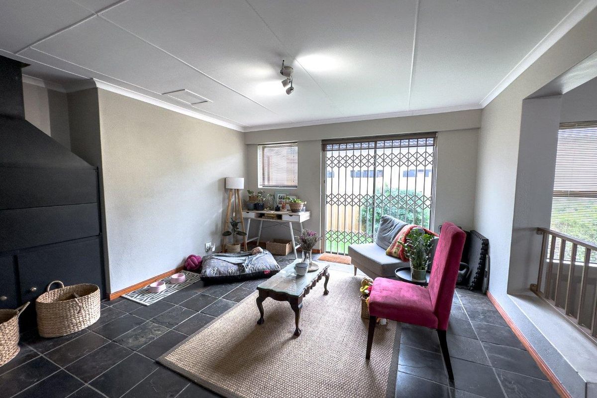 A living room featuring slate tile flooring, a built-in fireplace, and a sliding glass door with a security gate leading to the exterior.