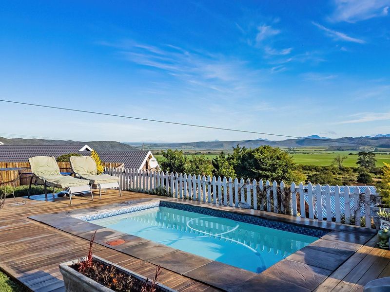 Outdoor pool area featuring timber decking, a picket fence, and expansive rural landscape views.