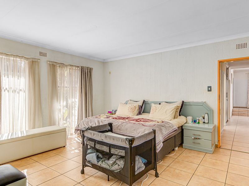 Spacious bedroom featuring tiled flooring, a built-in headboard with integrated bedside tables, and direct access to the hallway.