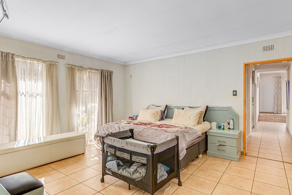Spacious bedroom featuring tiled flooring, a built-in headboard with integrated bedside tables, and direct access to the hallway.
