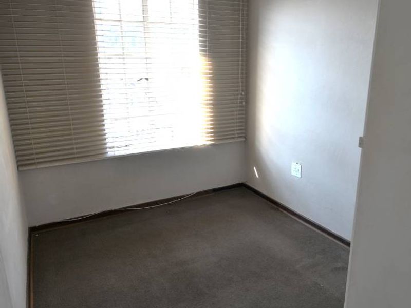 An empty bedroom featuring carpeted flooring, coved ceilings, and fitted venetian blinds, offering a blank canvas for potential interior design updates.