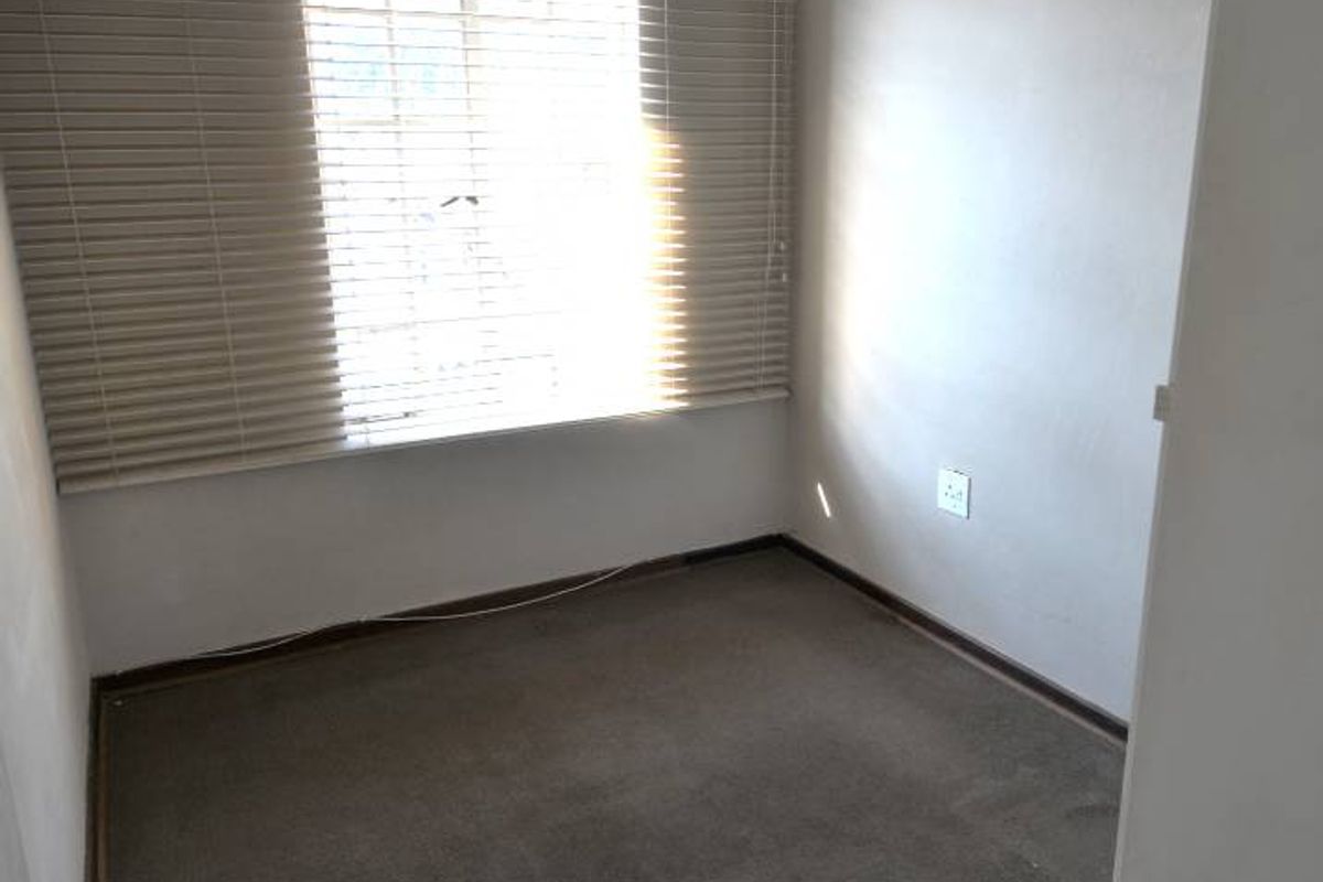 An empty bedroom featuring carpeted flooring, coved ceilings, and fitted venetian blinds, offering a blank canvas for potential interior design updates.