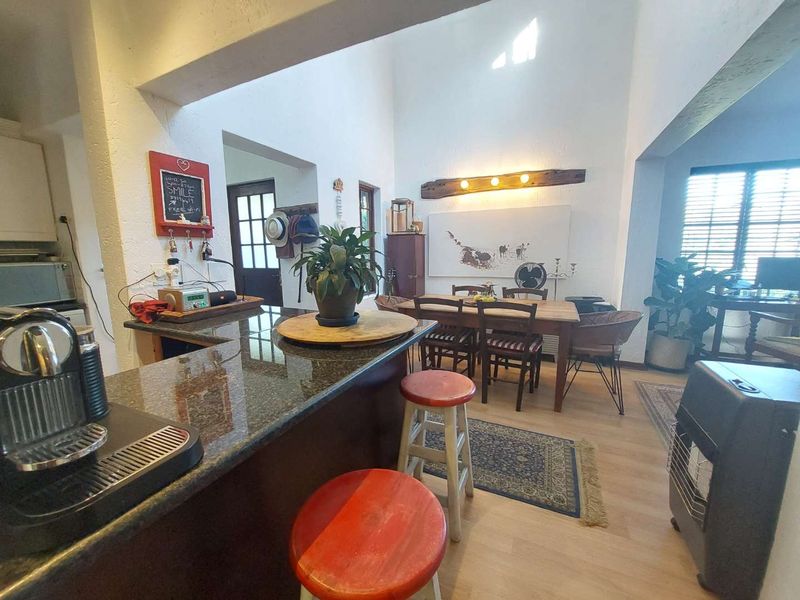 Open-plan living and dining area featuring a granite breakfast bar, high vaulted ceilings, and laminate flooring, creating a bright and spacious atmosphere.
