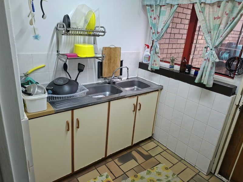 A functional scullery area featuring a double stainless steel sink, tiled splashback, and original cabinetry, offering potential for a modern renovation.