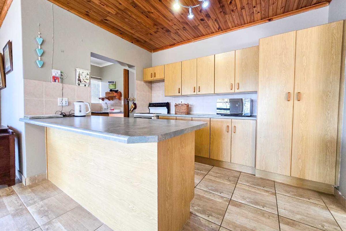 Functional kitchen featuring light wood cabinetry, tiled flooring, a breakfast bar, and a distinctive timber-paneled ceiling.